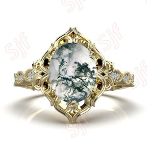 May include: A gold ring with a large oval-shaped moss agate gemstone set in a delicate filigree design. The ring band is adorned with small diamonds.
