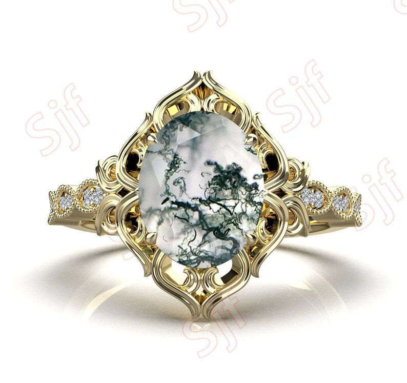 May include: A gold ring with a large oval-shaped moss agate gemstone set in a delicate filigree design. The ring band is adorned with small diamonds.
