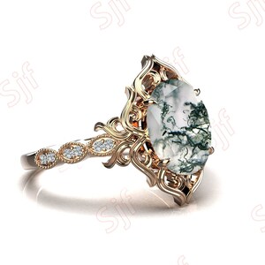 May include: A gold ring with a large oval-shaped moss agate gemstone set in a filigree design. The ring band is set with smaller diamonds.