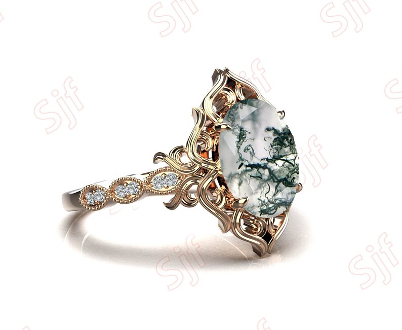May include: A gold ring with a large oval-shaped moss agate gemstone set in a filigree design. The ring band is set with smaller diamonds.