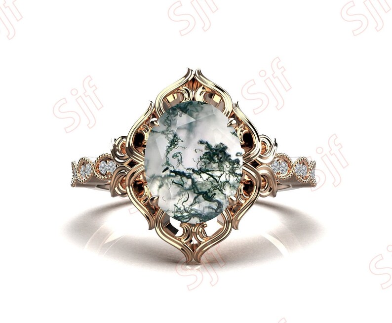 May include: A gold ring with a large oval-shaped moss agate gemstone set in a filigree design. The ring band is accented with small diamonds.