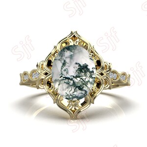 May include: A gold ring with a large oval-shaped moss agate gemstone set in a filigree design. The ring band is accented with small diamonds.