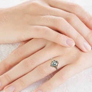 May include: A silver ring with a large, clear, faceted gemstone set in a delicate, ornate, gold-toned setting.