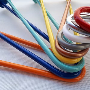 Pode incluir: Um conjunto de cabides de metal coloridos em vários tons de azul, laranja, amarelo, verde, cobre, cinza, branco e vermelho.