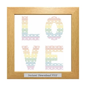 May include: A framed cross-stitch pattern of the word "LOVE" in rainbow colors with a heart design. The frame is light brown wood. The text "Instant Download PDF" is at the bottom of the frame.