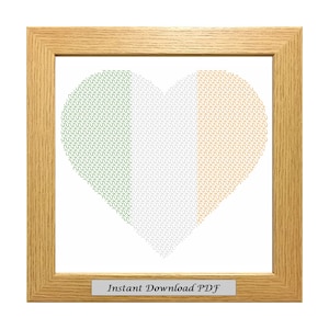 May include: A framed cross-stitch pattern of a heart shaped Irish flag. The heart is made up of green, white, and orange squares. The frame is light brown wood. The text "Instant Download PDF" is on a small plaque at the bottom of the frame.