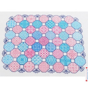 May include: A cross stitch pattern featuring a geometric design with octagons in shades of pink and blue. The pattern is surrounded by a border of blue and white.