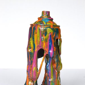 May include: A colorful abstract sculpture of a spray paint can with dripping paint, made of resin. The sculpture is on a black circular base.