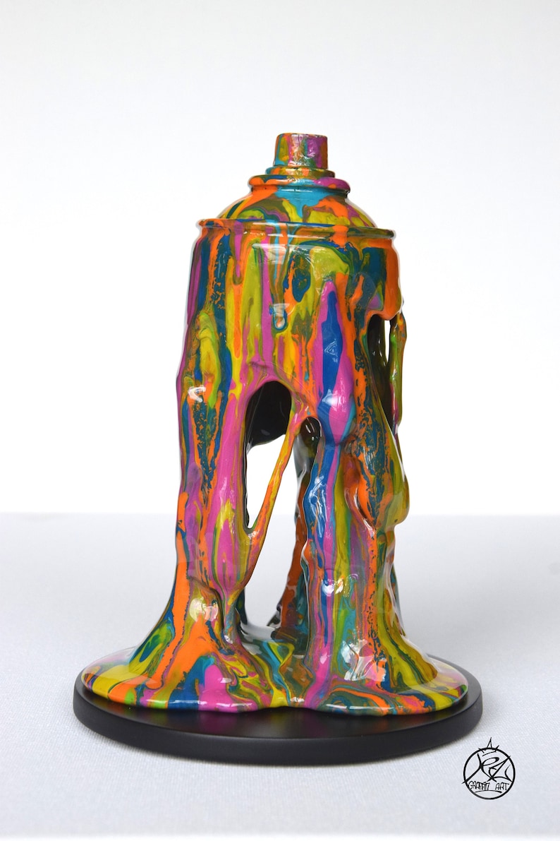 May include: A colorful abstract sculpture of a spray paint can with dripping paint, made of resin. The sculpture is on a black circular base.