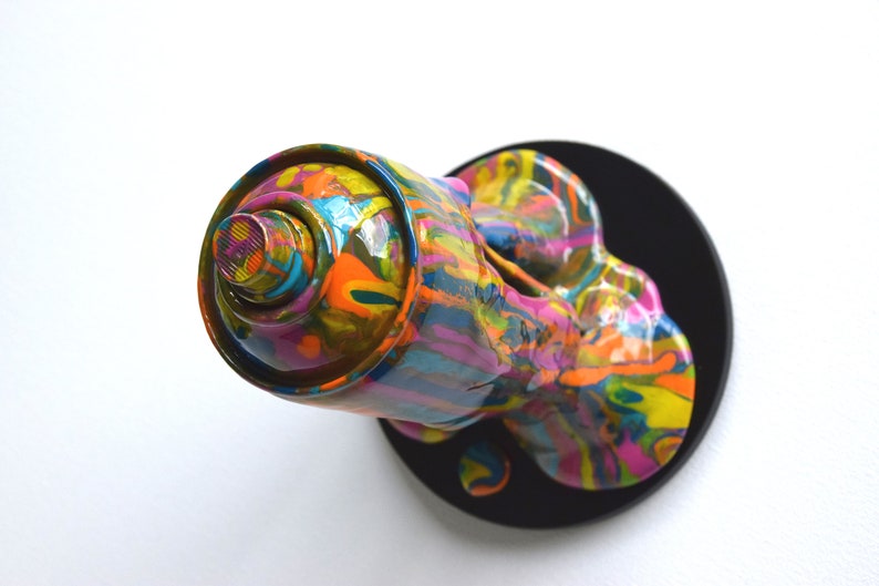 May include: A colorful spray paint can sculpture with a black base. The can is dripping with paint, creating a dynamic and abstract design.