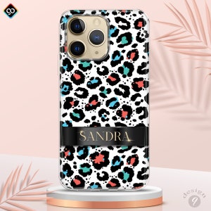 May include: A clear phone case with a white and black leopard print design. The case has a black band with the name "SANDRA" in gold lettering.