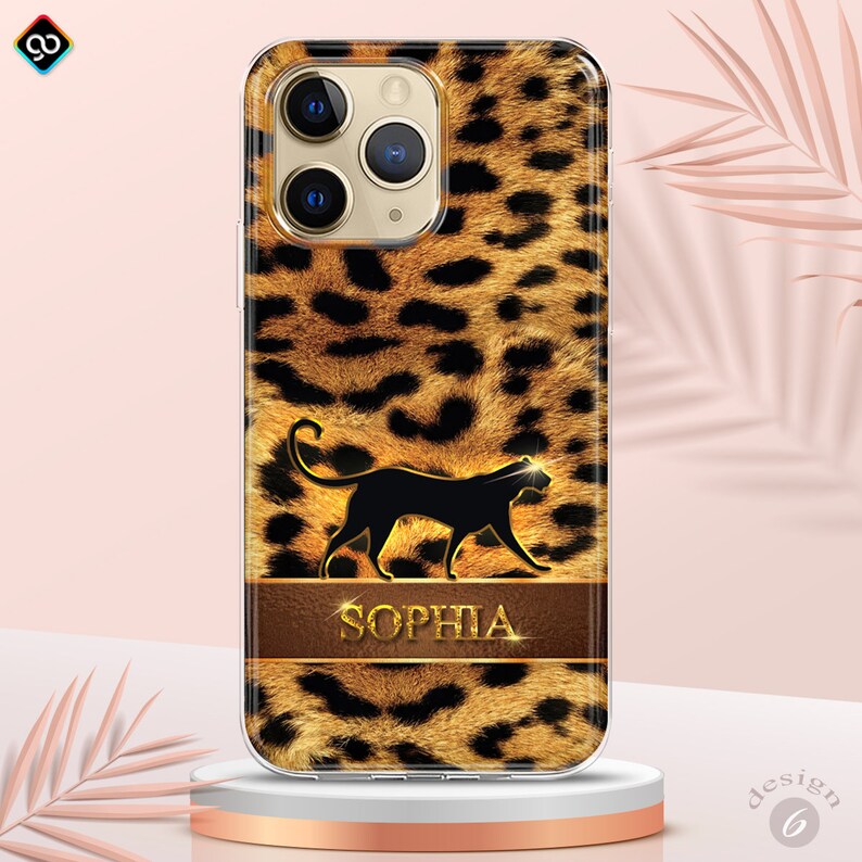 May include: A clear phone case with a leopard print design. The case features a black silhouette of a panther and the name "SOPHIA" in gold lettering on a brown leather-like band.
