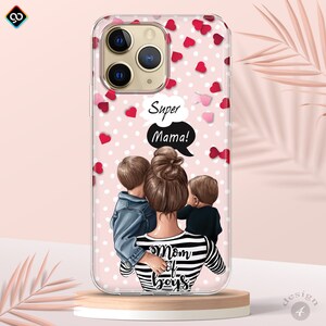 May include: A clear phone case with a pink background and white polka dots. The case features a cartoon illustration of a woman with two children, with the text "Super Mama!" in a speech bubble. The woman is wearing a striped shirt with the text "Mom of Boys" on it. The case is decorated with red and pink hearts.