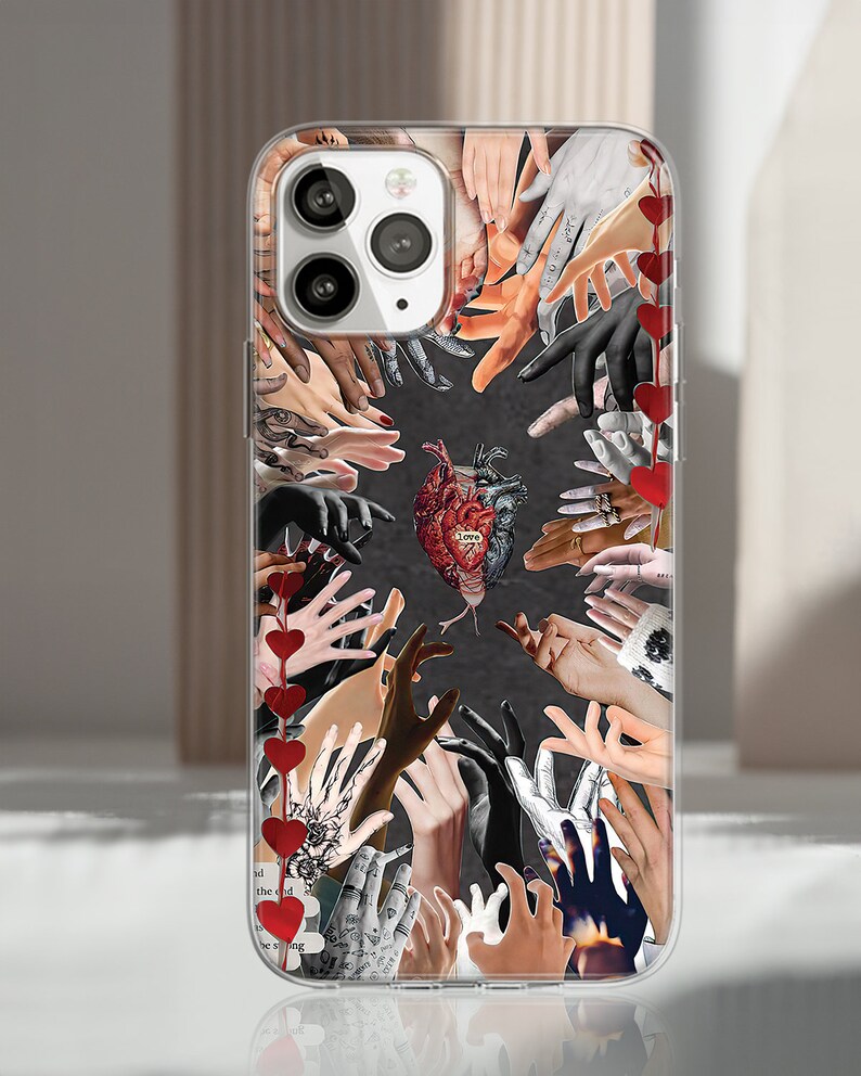Puede incluir: Funda transparente para tel&eacute;fono con un collage de manos convergiendo en una imagen central de un coraz&oacute;n. Las manos muestran diversos tonos de piel y estilos, algunos con tatuajes. Decoraciones rojas en forma de coraz&oacute;n cuelgan de una cuerda.