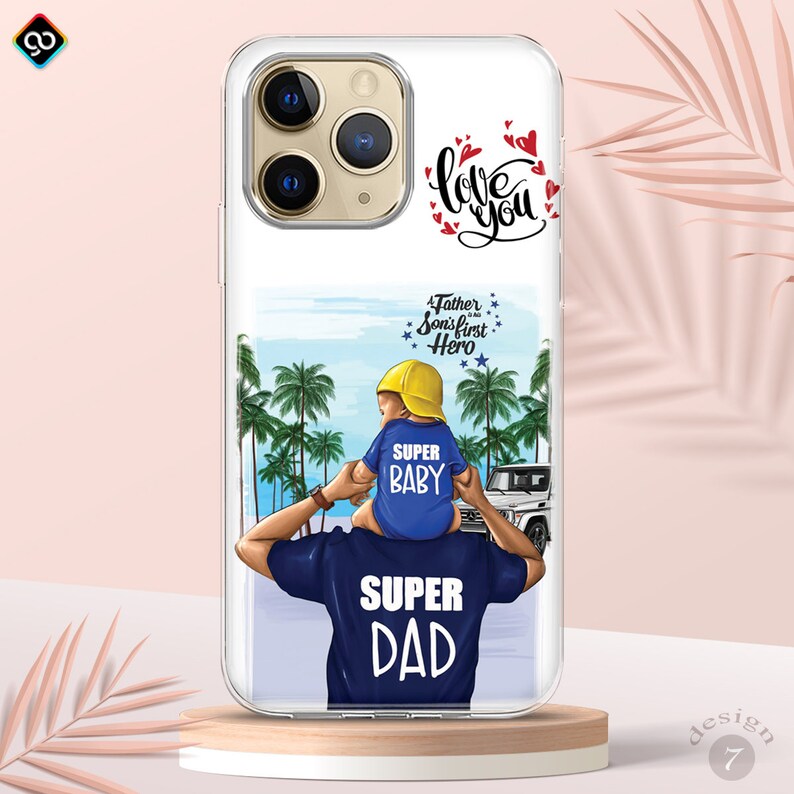 May include: A clear phone case with a colorful illustration of a father and son on a beach. The father is carrying the son on his shoulders. The son is wearing a yellow hat and a blue shirt that says "Super Baby". The father is wearing a blue shirt that says "Super Dad". The text "Love You" is written in black on the top of the case. The text "A Father is his Son's First Hero" is written in black on the bottom of the case.