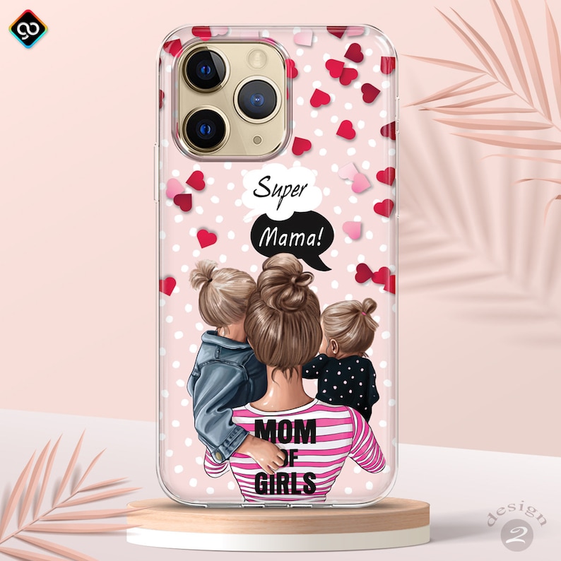 May include: A clear phone case with a pink and white background. The case features a cartoon illustration of a woman with two children, with the text "Super Mama!" and "Mom of Girls".