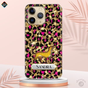 May include: A clear phone case with a pink and gold leopard print design. The case features a gold cheetah silhouette and a nameplate with the name "SANDRA" in gold lettering.