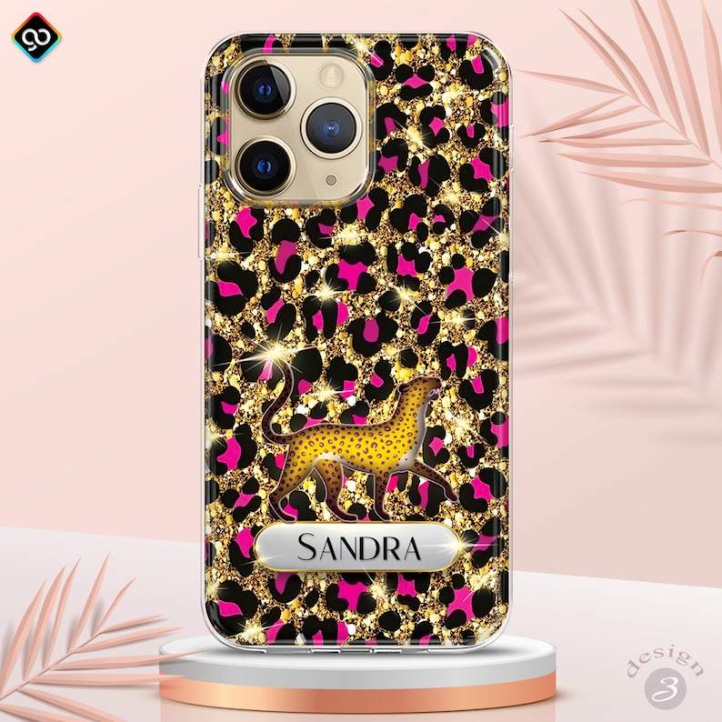 May include: A clear phone case with a pink and gold leopard print design. The case features a gold cheetah silhouette and a nameplate with the name "SANDRA" in gold lettering.