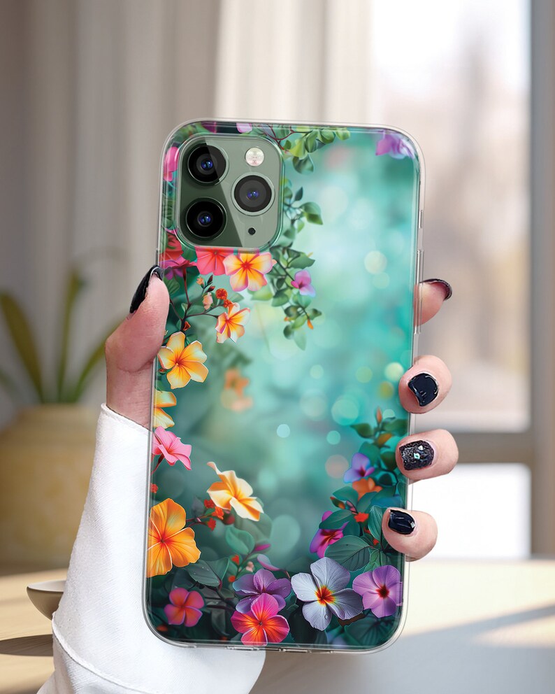 May include: Clear phone case with a floral design. The case features a variety of colorful flowers, including pink, purple, yellow, and orange, on a green and blue background.