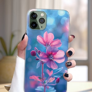 May include: A clear phone case with a floral design. The case features a pink flower with a blue background and bokeh effect.