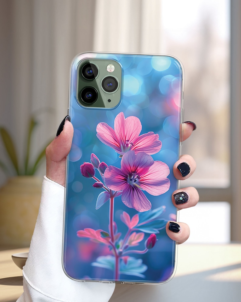 May include: A clear phone case with a floral design. The case features a pink flower with a blue background and bokeh effect.