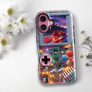 May include: Clear phone case with a colorful design resembling a retro handheld game console. The case features a pink camera cutout and a screen displaying a car racing scene. The design includes buttons, circuits, and the word "GAMEBOX".
