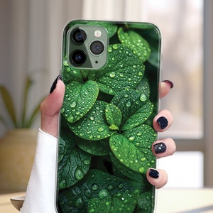 May include: A clear phone case with a green leafy design. The leaves have water droplets on them.