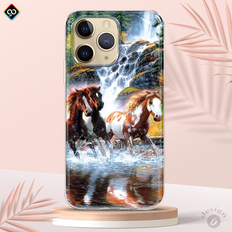 Op de afbeelding: Een transparante telefoonhoes met een kleurrijk beeld van drie paarden die door een waterval rennen. De paarden zijn bruin, wit en zwart met spatten water eromheen.