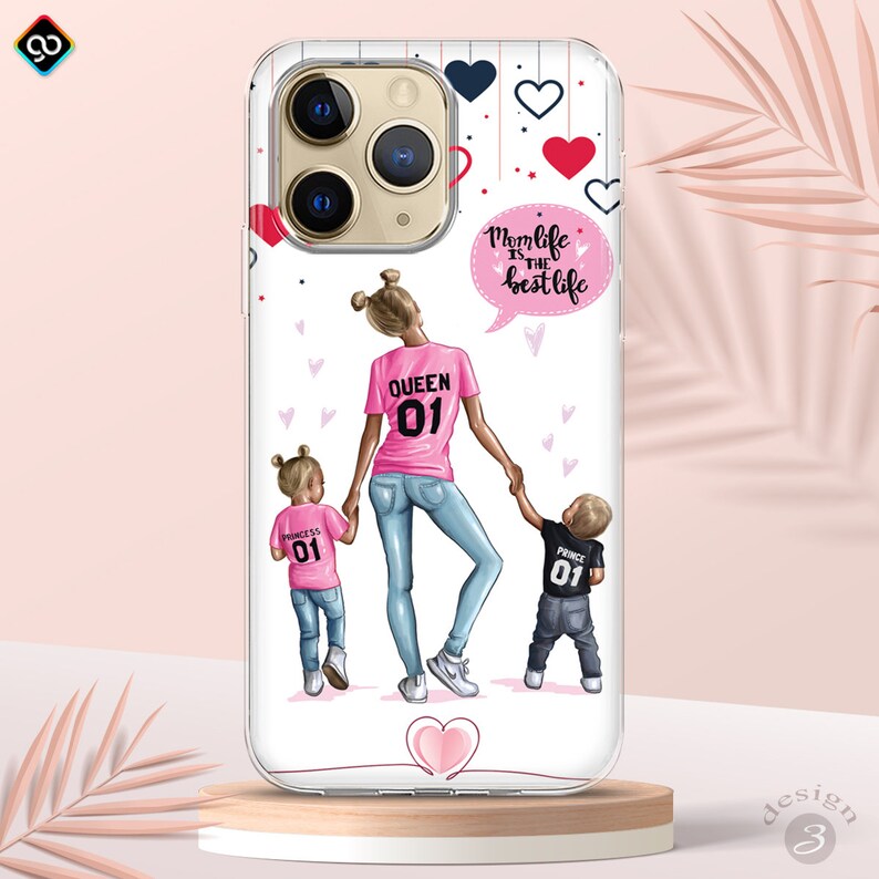May include: White phone case with a cartoon illustration of a mother and two children. The mother is wearing a pink shirt with the text "Queen 01" and blue jeans. The daughter is wearing a pink shirt with the text "Princess 01" and blue jeans. The son is wearing a black shirt with the text "Prince 01" and blue jeans. The case has a speech bubble with the text "Mom life is the best life" and hearts in various colors.
