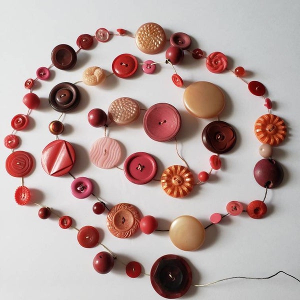 Vintage button garland in pinks and reds. 5' 2" on hemp cord.