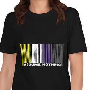 Könnte beinhalten: Schwarzes T-Shirt mit einem Barcode-Design in Gelb, Weiß, Lila und Schwarz. Der Text "ASSUME NOTHING" ist unter dem Barcode aufgedruckt.