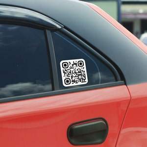 May include: A red car with a black window and a white square sticker with a black QR code on the back window.