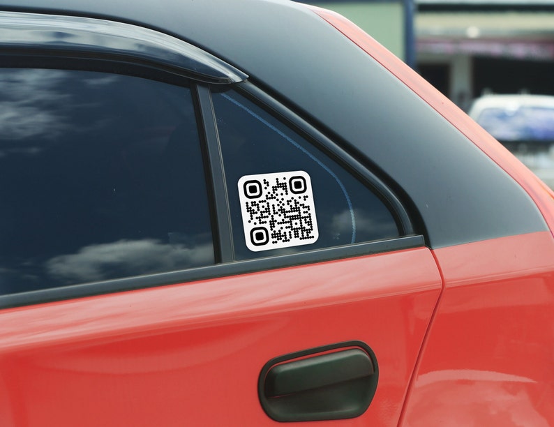 May include: A red car with a black window and a white square sticker with a black QR code on the back window.