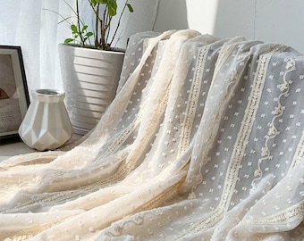 May include: White sheer fabric with a delicate dot pattern and embroidered lace trim. The fabric has a soft, flowing texture and is perfect for crafting projects.