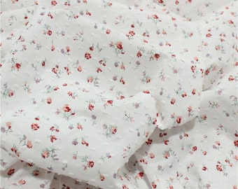 May include: White cotton fabric with a small, red and pink floral pattern. The fabric has a textured, dotted surface.