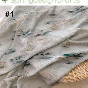 Peut inclure: Tissu blanc cass&eacute; avec un motif de paysage repr&eacute;sentant des montagnes, de l'eau et des bateaux. Le tissu a un aspect aquarelle avec des tons verts, bruns et gris. Le texte "SpringdesignCrafts" et "#1" sont visibles.