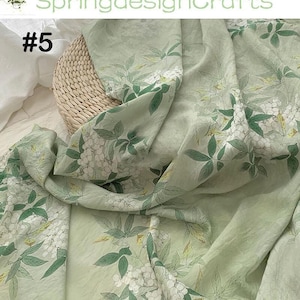 Peut inclure: Tissu vert clair avec un motif floral de fleurs blanches et de feuilles vertes. Le tissu est drap&eacute; sur un panier en osier. Le texte "SpringdesignCrafts" et "#5" sont visibles.