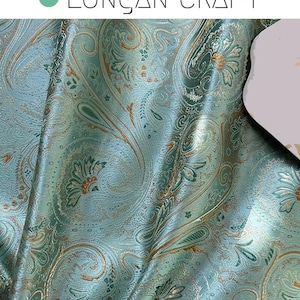 May include: Teal fabric with a paisley pattern in gold and green. The fabric has a subtle sheen and a textured surface.