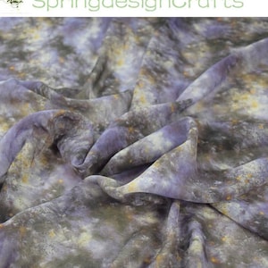 May include: A close-up shot of a fabric with a watercolour design. The fabric has a mix of grey, lavender, and yellow tones, giving it a soft, textured look. The fabric is draped, showing folds and shadows. The text "SpringdesignCrafts" is in the upper left corner.