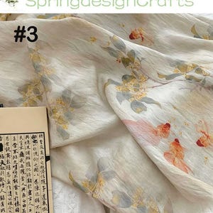 Peut inclure: Tissu blanc cass&eacute; avec un imprim&eacute; floral et de poissons rouges. Le motif pr&eacute;sente des accents orange, jaune et rose. Le texte "#3" est visible sur le tissu. Le nom de la boutique "SpringdesignCrafts" est en haut.
