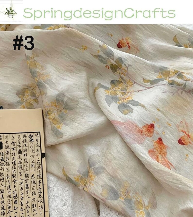 Peut inclure: Tissu blanc cass&eacute; avec un imprim&eacute; floral et de poissons rouges. Le motif pr&eacute;sente des accents orange, jaune et rose. Le texte "#3" est visible sur le tissu. Le nom de la boutique "SpringdesignCrafts" est en haut.