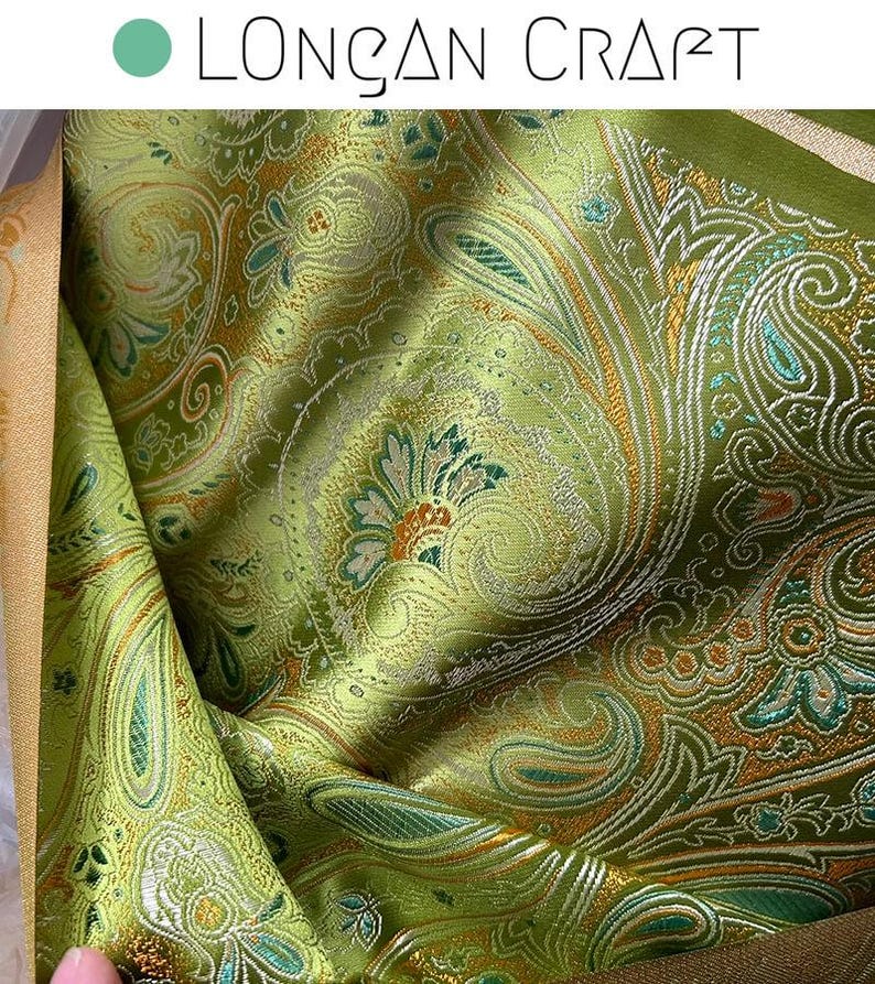 May include: Green paisley fabric with gold and silver accents. The fabric has a textured, woven look.