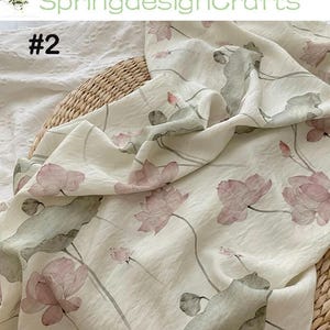 Peut inclure: Tissu blanc cass&eacute; avec un motif floral d&eacute;licat de fleurs de lotus roses et de feuilles vertes. Le tissu est drap&eacute; sur un panier en osier. Le texte "SpringdesignCrafts" et "#2" sont visibles.
