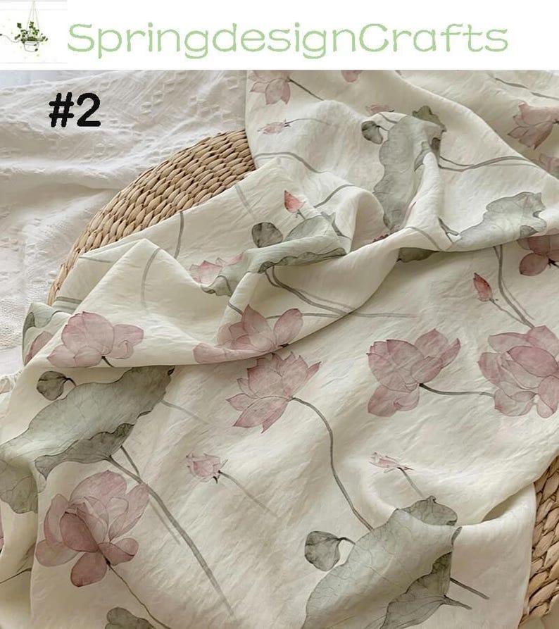 Peut inclure: Tissu blanc cass&eacute; avec un motif floral d&eacute;licat de fleurs de lotus roses et de feuilles vertes. Le tissu est drap&eacute; sur un panier en osier. Le texte "SpringdesignCrafts" et "#2" sont visibles.