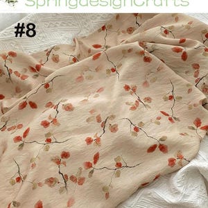 Peut inclure: Un tissu beige clair avec un motif floral d&eacute;licat de feuilles et de branches rouges et marron. Le tissu est l&eacute;g&egrave;rement froiss&eacute;, avec le texte "SpringdesignCrafts" et "#8" visible.