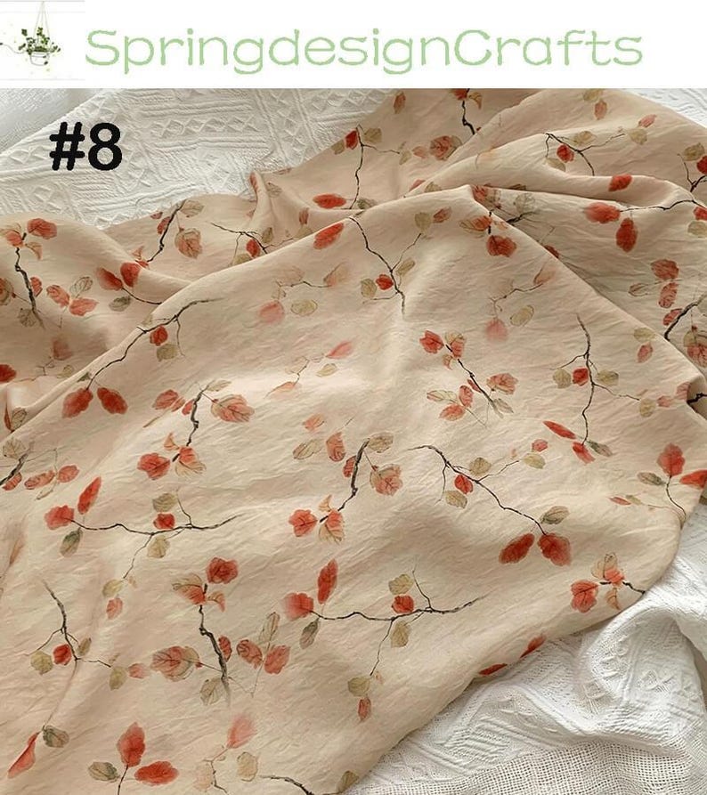 Peut inclure: Un tissu beige clair avec un motif floral d&eacute;licat de feuilles et de branches rouges et marron. Le tissu est l&eacute;g&egrave;rement froiss&eacute;, avec le texte "SpringdesignCrafts" et "#8" visible.