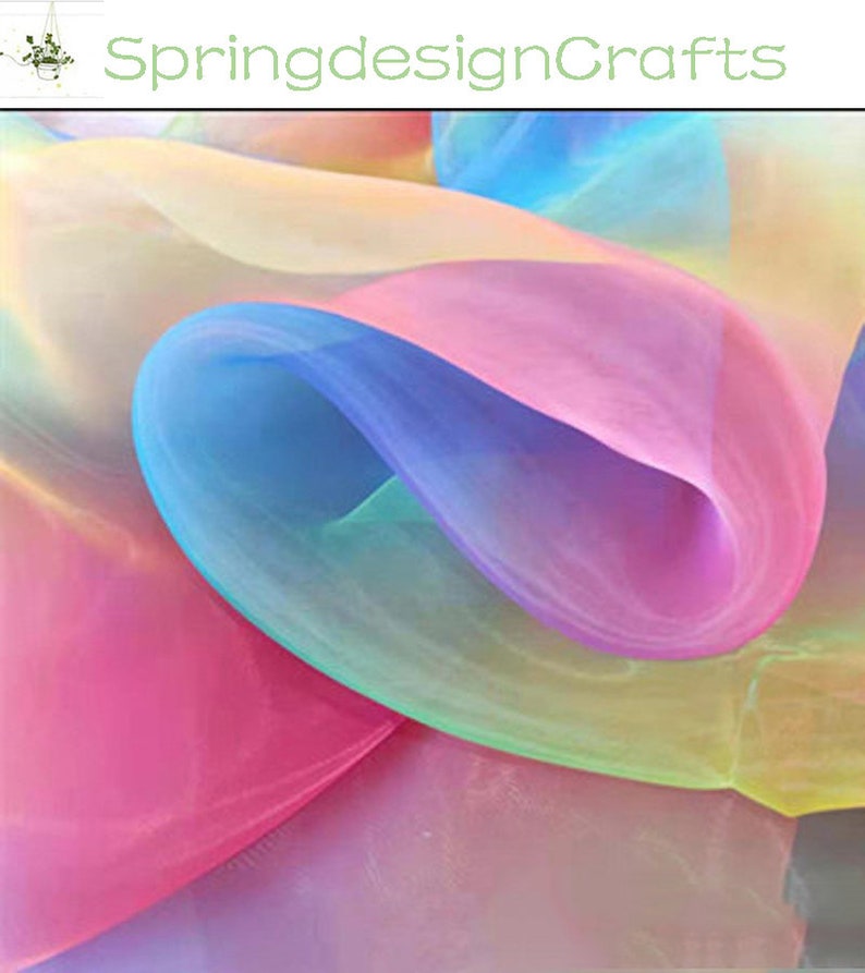 May include: A close-up of flowing, sheer fabric in a spectrum of colors, including pink, blue, yellow, and purple. The fabric is layered and creates a soft, ethereal effect. The text "SpringdesignCrafts" is in the upper left corner.