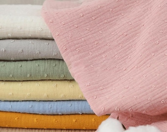 May include: A stack of different coloured fabric swatches with a dotted texture. The fabric is soft and has a subtle sheen. The swatches are arranged in a pyramid shape with the largest swatch at the bottom and the smallest swatch at the top. The fabric is a popular choice for crafting and sewing projects.
