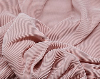May include: A soft, light pink fabric featuring a dense, vertical pleated texture. The material is draped in folds, highlighting the consistent, narrow ridges that run throughout the length of the textile. The text SpringdesignCrafts is visible.
