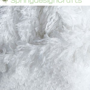 May include: White feather trim fabric with a delicate, lacy texture. The fabric is soft and airy, perfect for adding a touch of elegance to any project.
